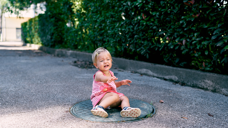 girl crying on manhole cover