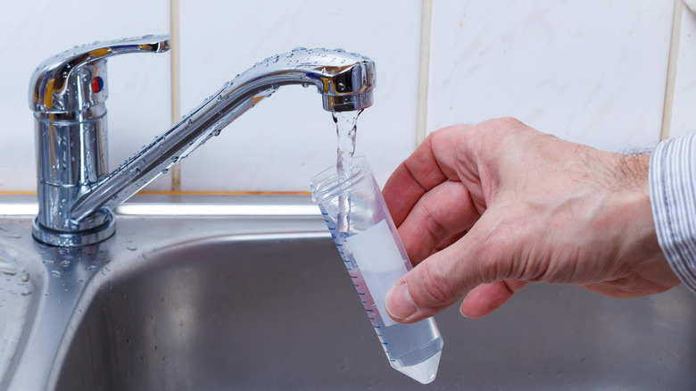 Man holding container under faucet