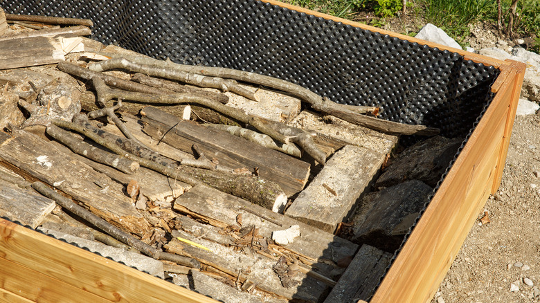 Wooden logs at the bottom of a raised garden bed