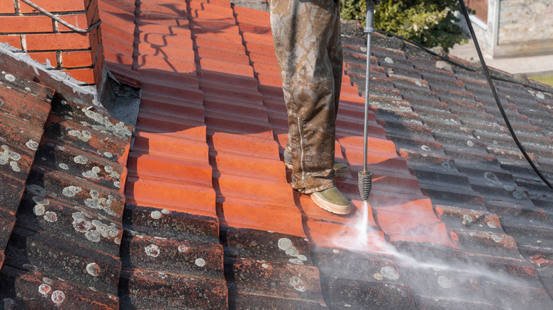 person pressure washing roof