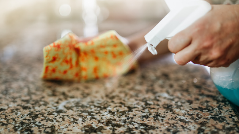 A person spraying granite countertops with cleaner