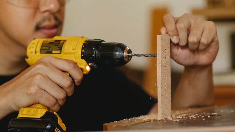 Man drilling small holes with power drill