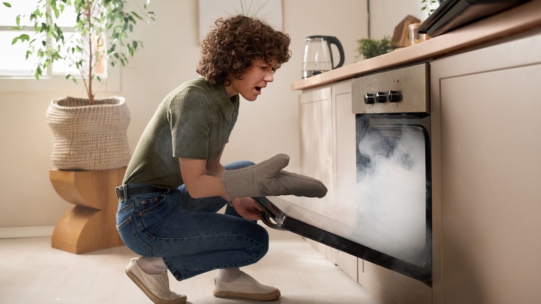 woman opening oven filled with smoke