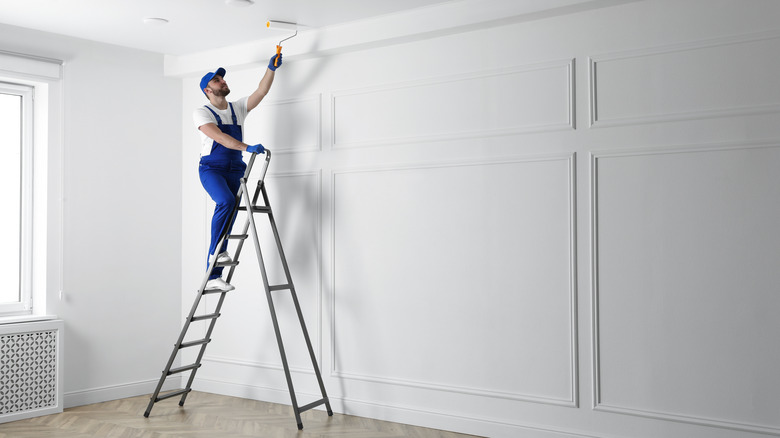 man painting ceiling on ladder