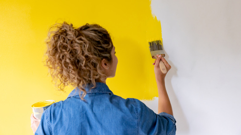 Woman painting wall yellow