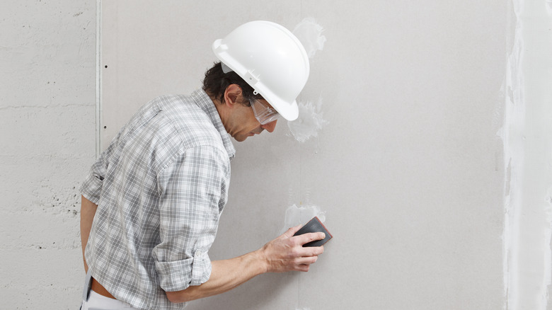 Man sanding wall