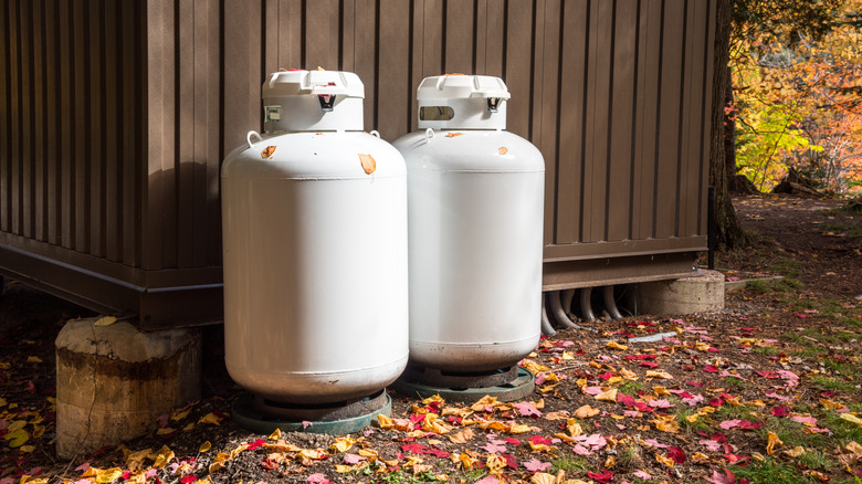 A pair of propane tanks sitting outside a metal shed