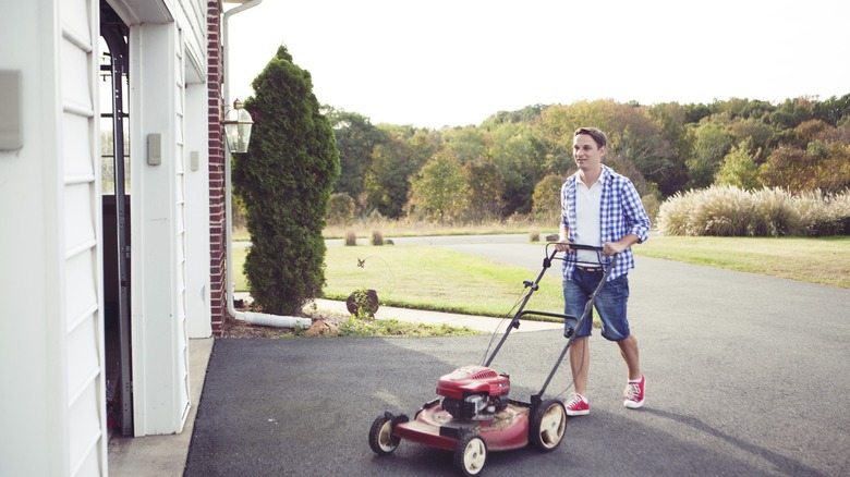 man putting lawn mower garage