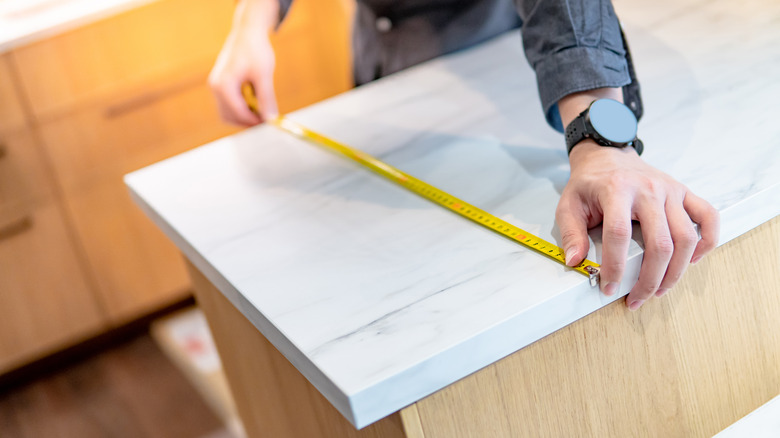 person measuring kitchen countertop