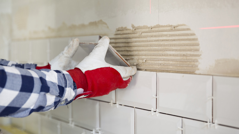 person installing tile backsplash