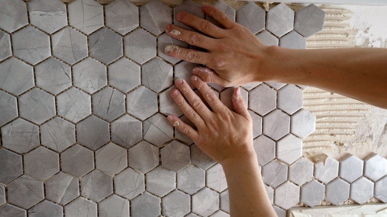 Woman placing ceramic wall tile 