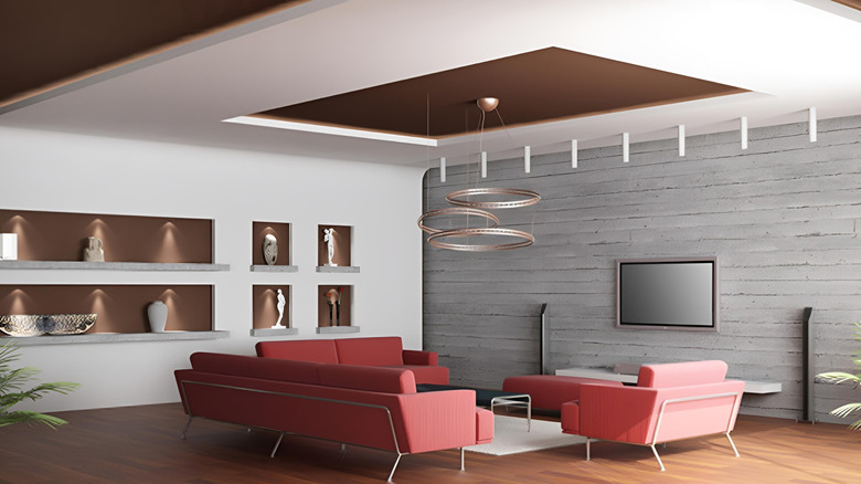 A false ceiling in a stylish living room with a modern lighting fixture above sofas