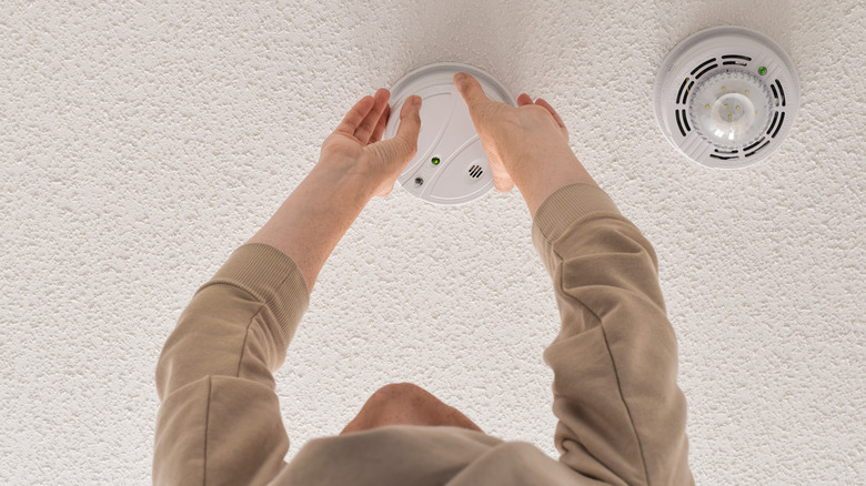 Person replacing carbon monoxide alarm 