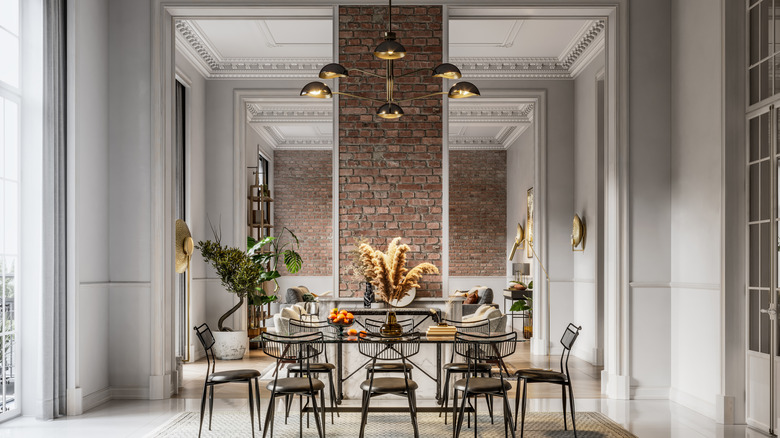 A room with a large, modern chandelier hanging over a dining room table