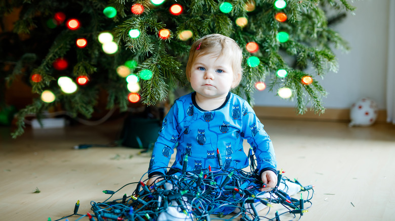 baby holding Christmas lights