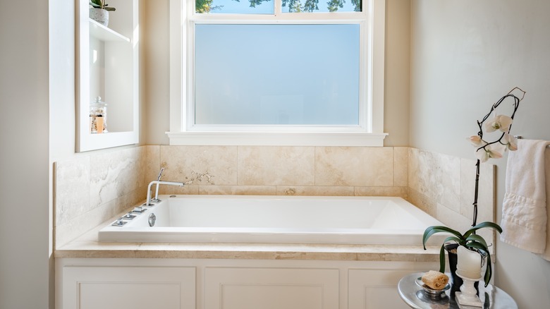 Bathtub featuring beige travertine tiles in bathroom