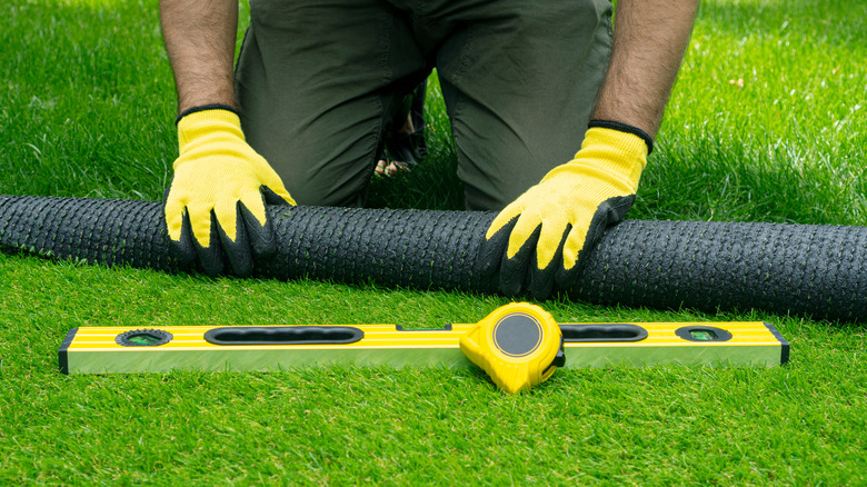 person leveling artificial turf roll