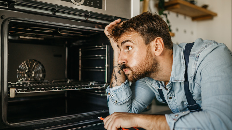 man confused looking inside oven