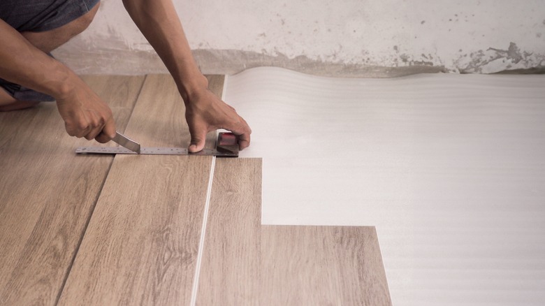 Hands cutting vinyl flooring