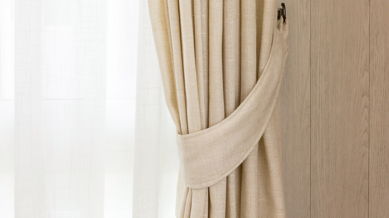 pleated natural linen blackout curtain in front of white sheer curtain