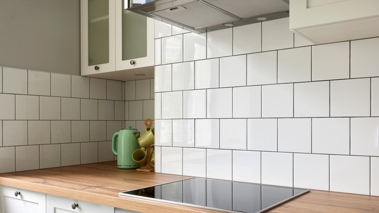 A kitchen with white square tile backsplash