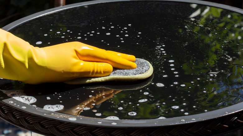 Wiping outdoor table with Windex