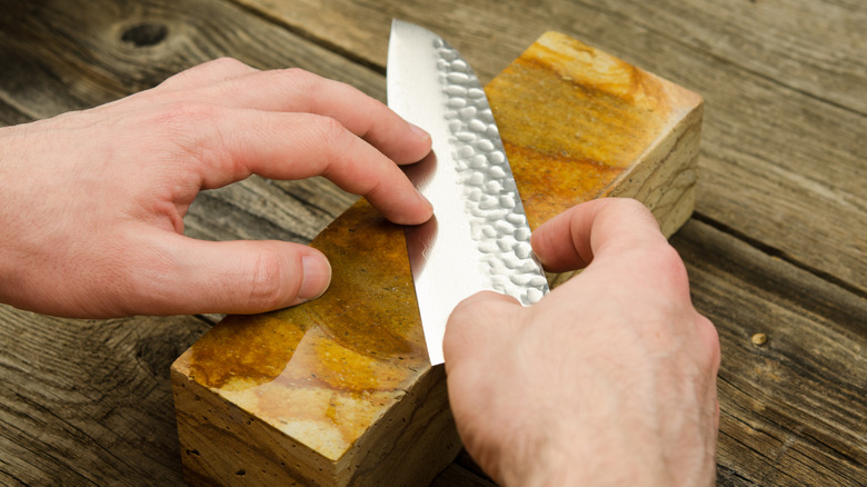 Person sharpening knife using whetstone