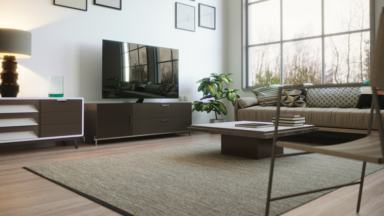 A modern living room features a flat screen tv, plants, and neutral furnishings