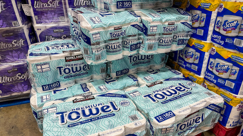 Kirkland brand paper towels and Scott toilet paper are stacked on palettes at Costco