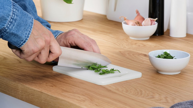 Person chopping herbs on an IKEA LEGITIM chopping board.