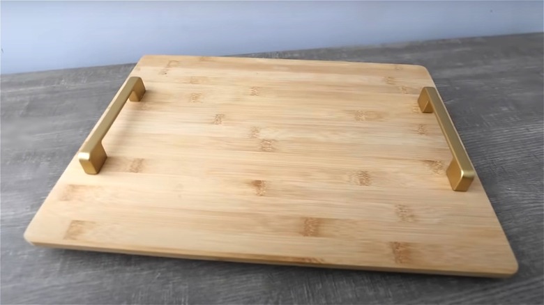 Wooden tray with golden handles on gray surface