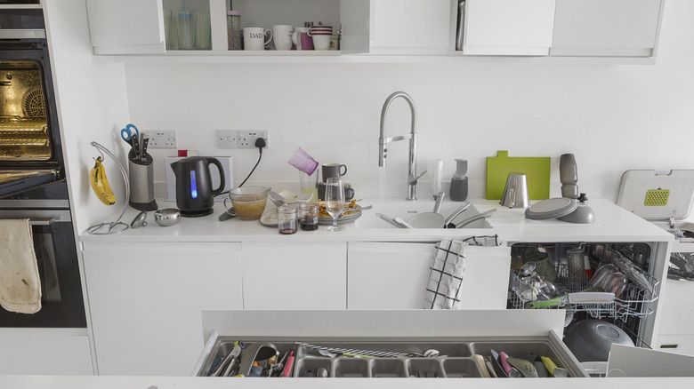 The kitchen has dishes and cooking utensils everywhere