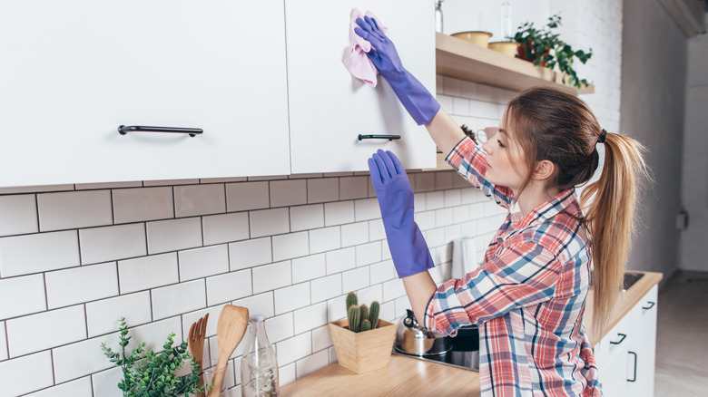 Woman wiping kitchen cabinet