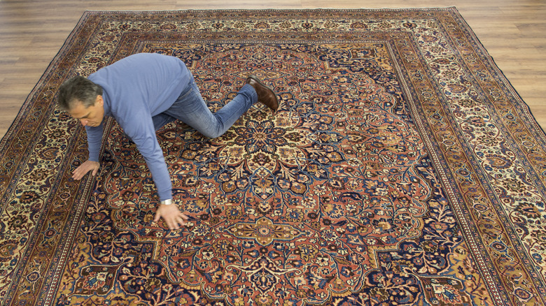 man looking at rug