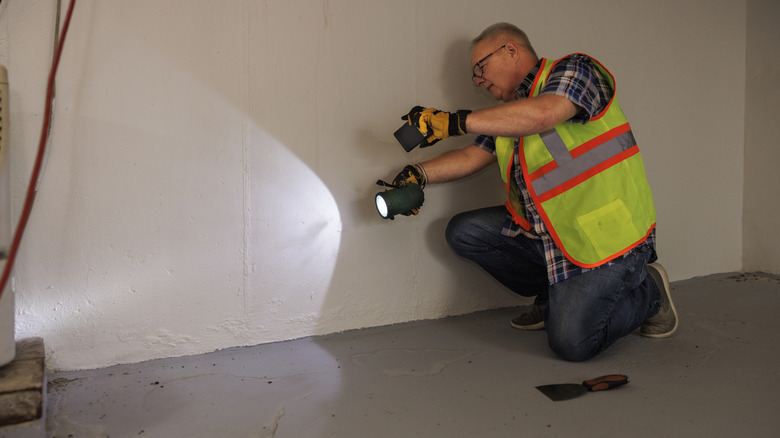 A person with a flashlight looking for water damage in a basement