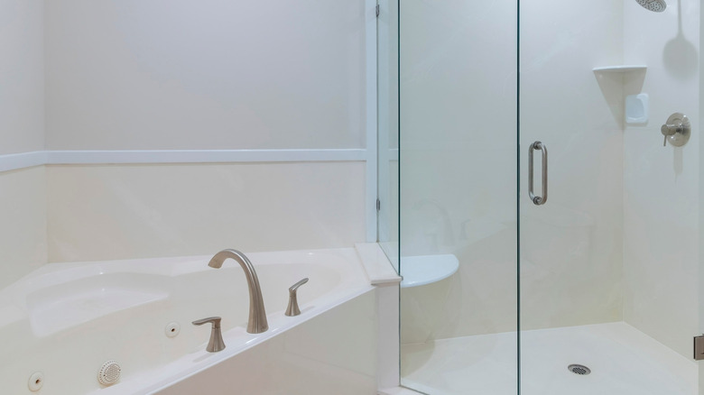 A bathroom with an acrylic corner tub and standing shower