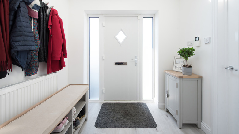 Entryway with gray credenza cabinet, bench, and coat hooks.