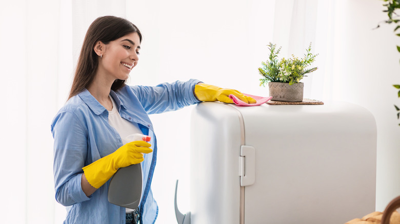 woman cleaning top of fridge