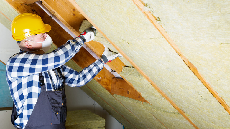 Man installing insulation in attic ceiling