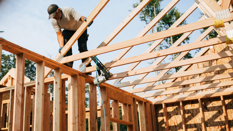 A construction worker builds a wooden house frame