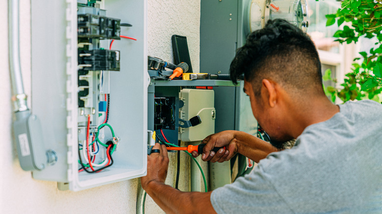 Man fixing a circuit breaker box located outside