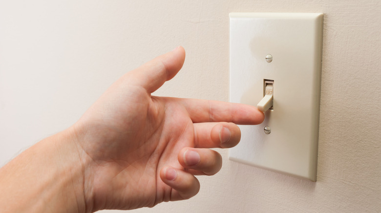 Hand flipping a light switch from off to on