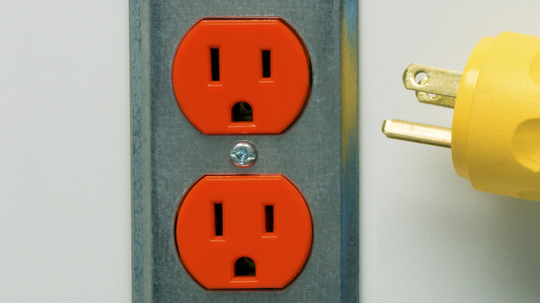 A plug depicted next to an orange outlet with steel cover plate