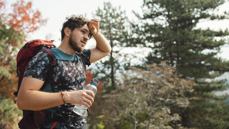 Man wiping forehead outdoors