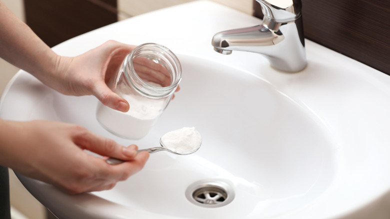 Person pouring baking soda into sink