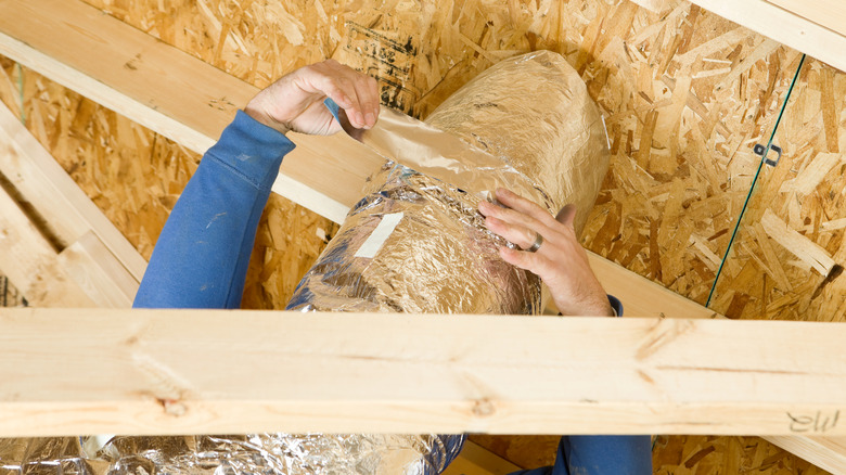 worker sealing attic vent duct