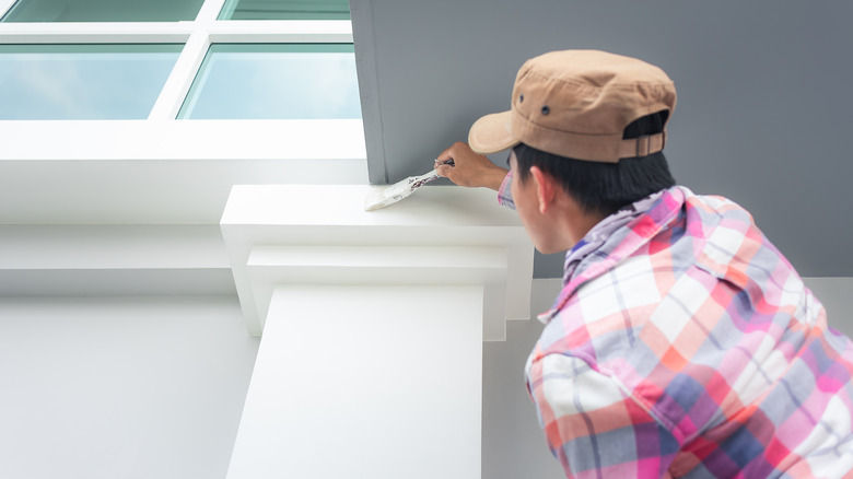 man painting house white