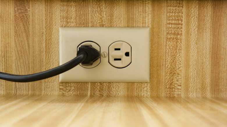 A white electrical outlet with an appliance plugged in