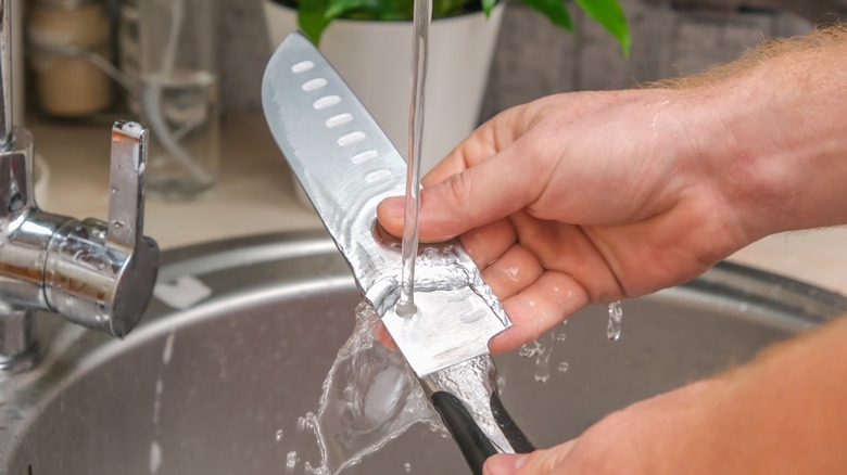 person washing knife 