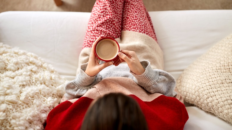 Person on couch holding mug of hot cocoa